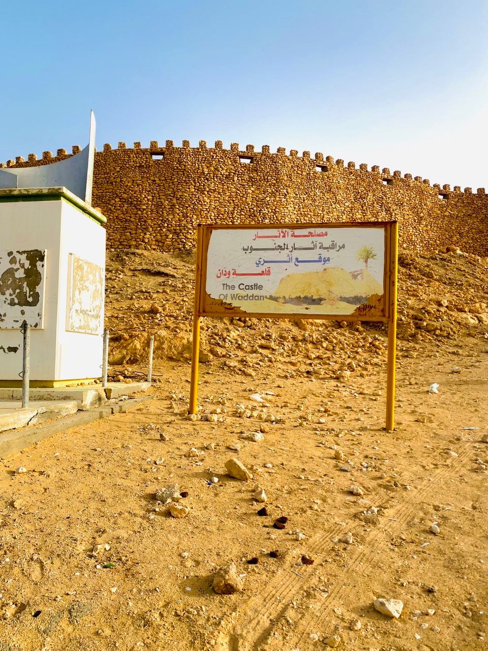 Waddan Castle and its heritage sign in the desert landscape.